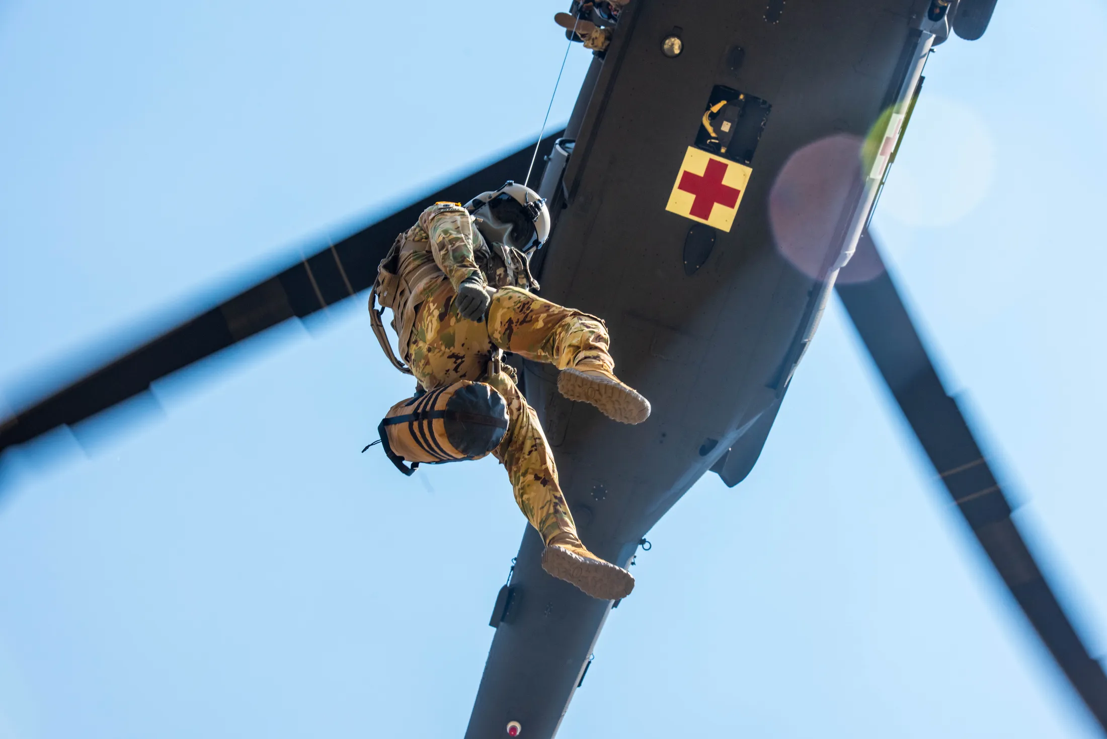 Idaho Army National Guard crew member rides the rescue hoist beneath a UH-60 Black Hawk medevac helicopter, photo by Rusty Rehl