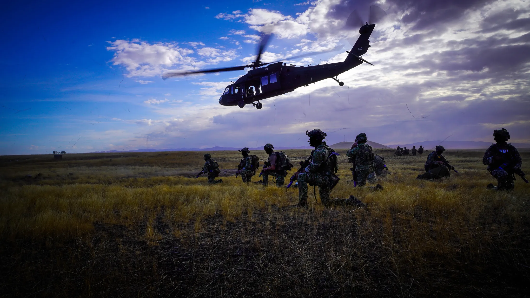 UH-60 Black Hawk lifts off at dusk over a kneeling FBI team during Exercise Hellgate at Camp Orchard, Idaho, photo by Rusty Rehl