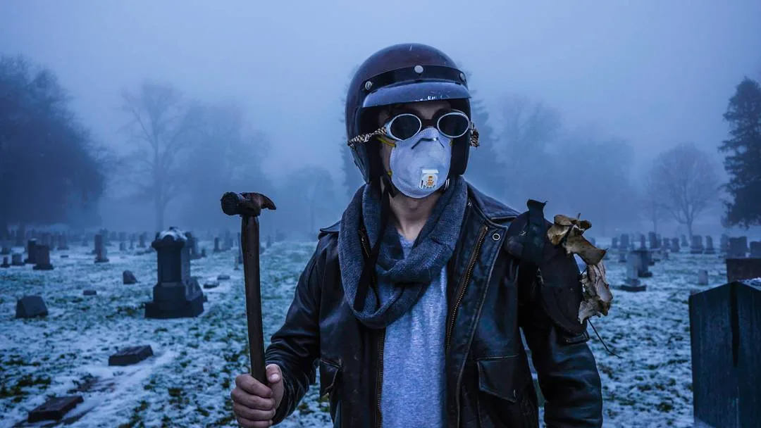 Still from a Rusty Rehl short film: a figure in a helmet, goggles and dust mask holds a hammer in a foggy cemetery