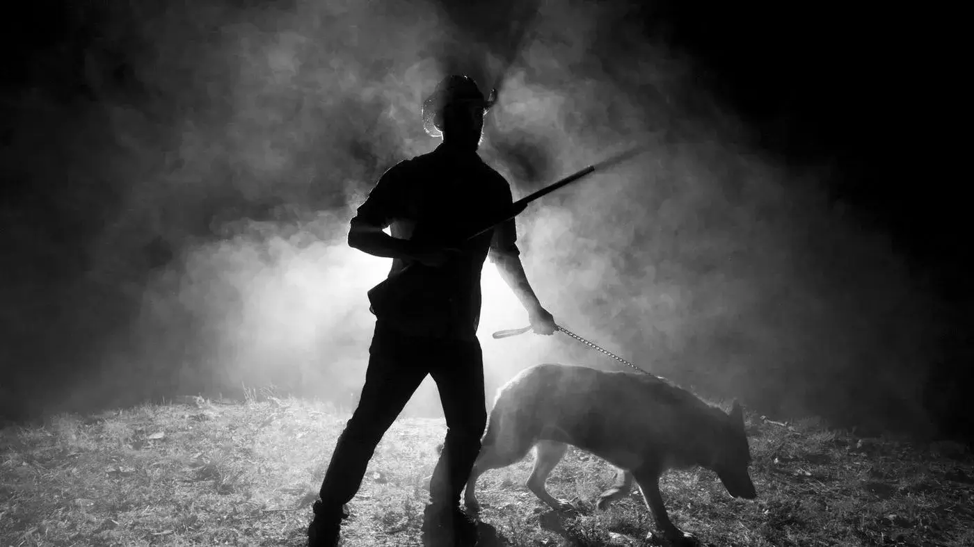 Black-and-white silhouette of a handler and dog in backlit smoke, Idaho, photo by Rusty Rehl