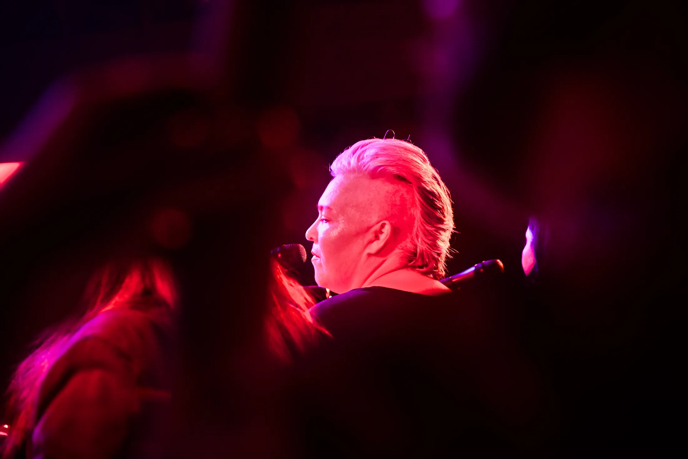 Singer with white swept-back hair in magenta stage light, Boise, Idaho concert photo by Rusty Rehl