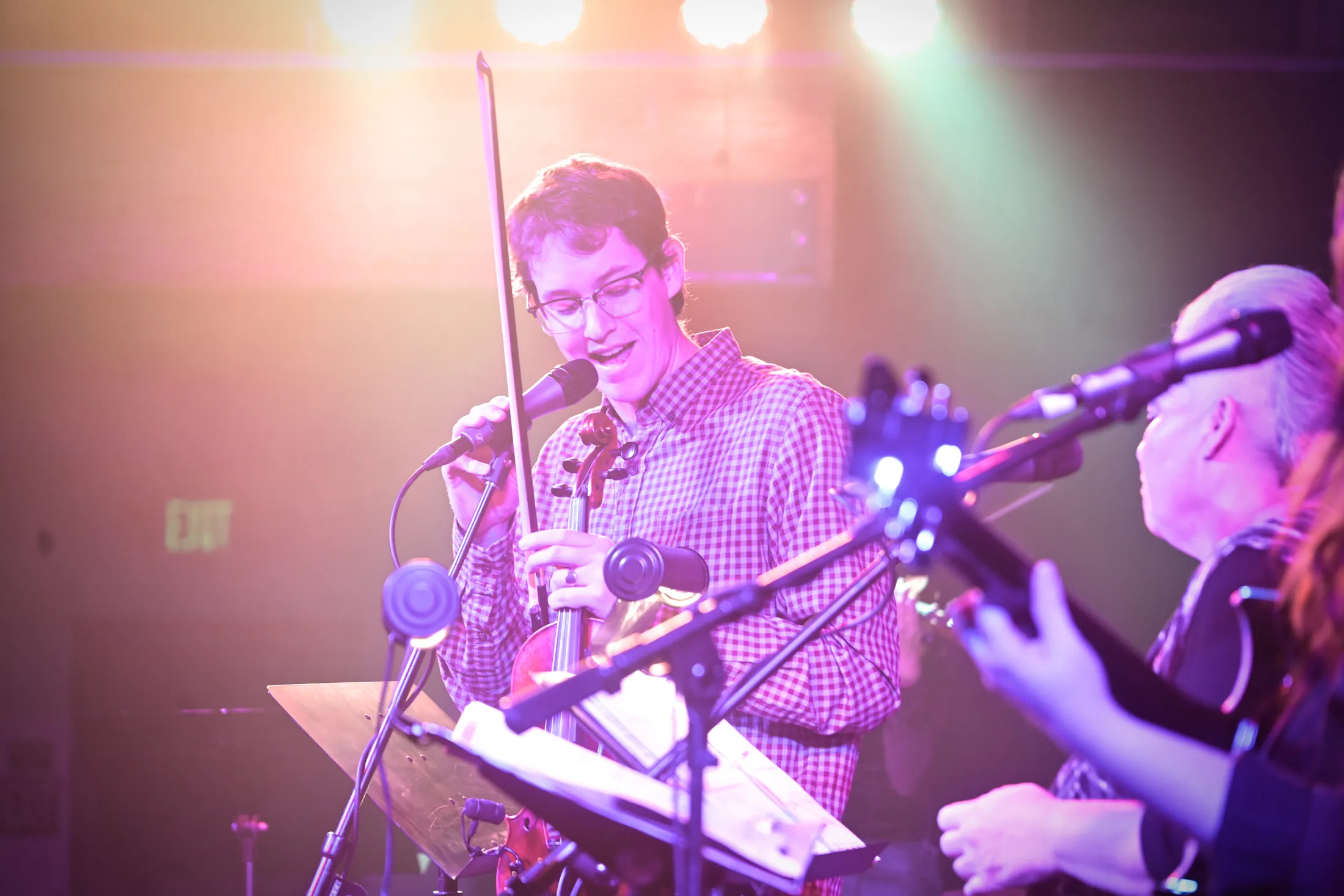 Violinist singing into the microphone under warm stage lights, Boise, Idaho concert photo by Rusty Rehl