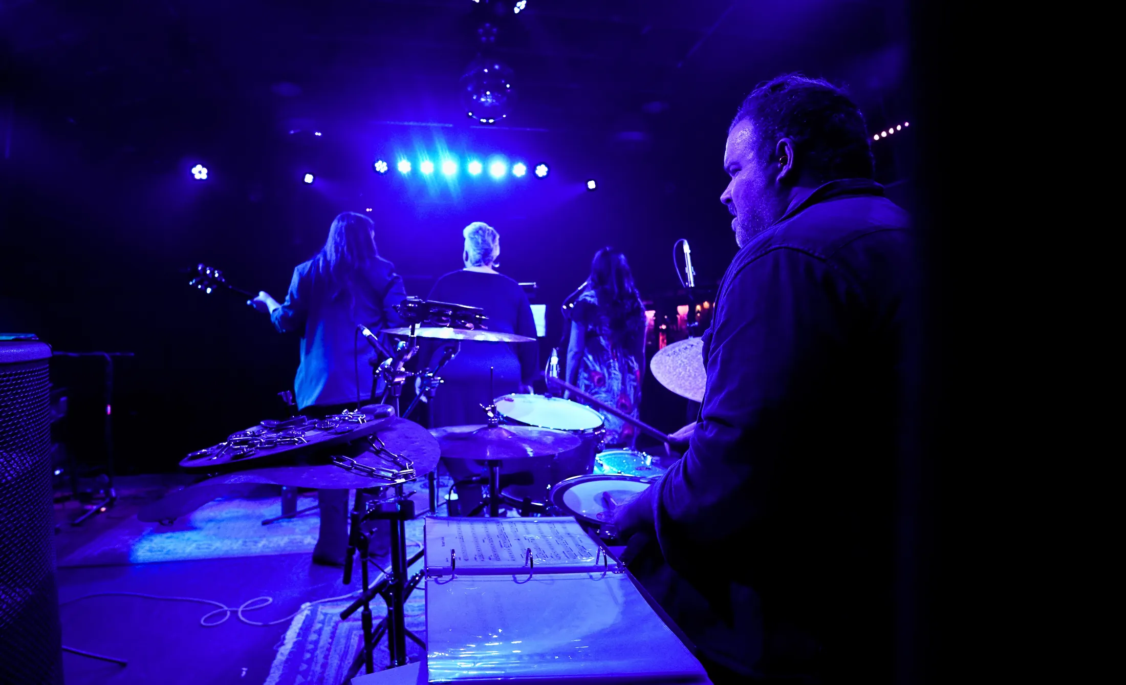 Looking out from behind the stage gear under blue lights, Boise, Idaho concert photo by Rusty Rehl