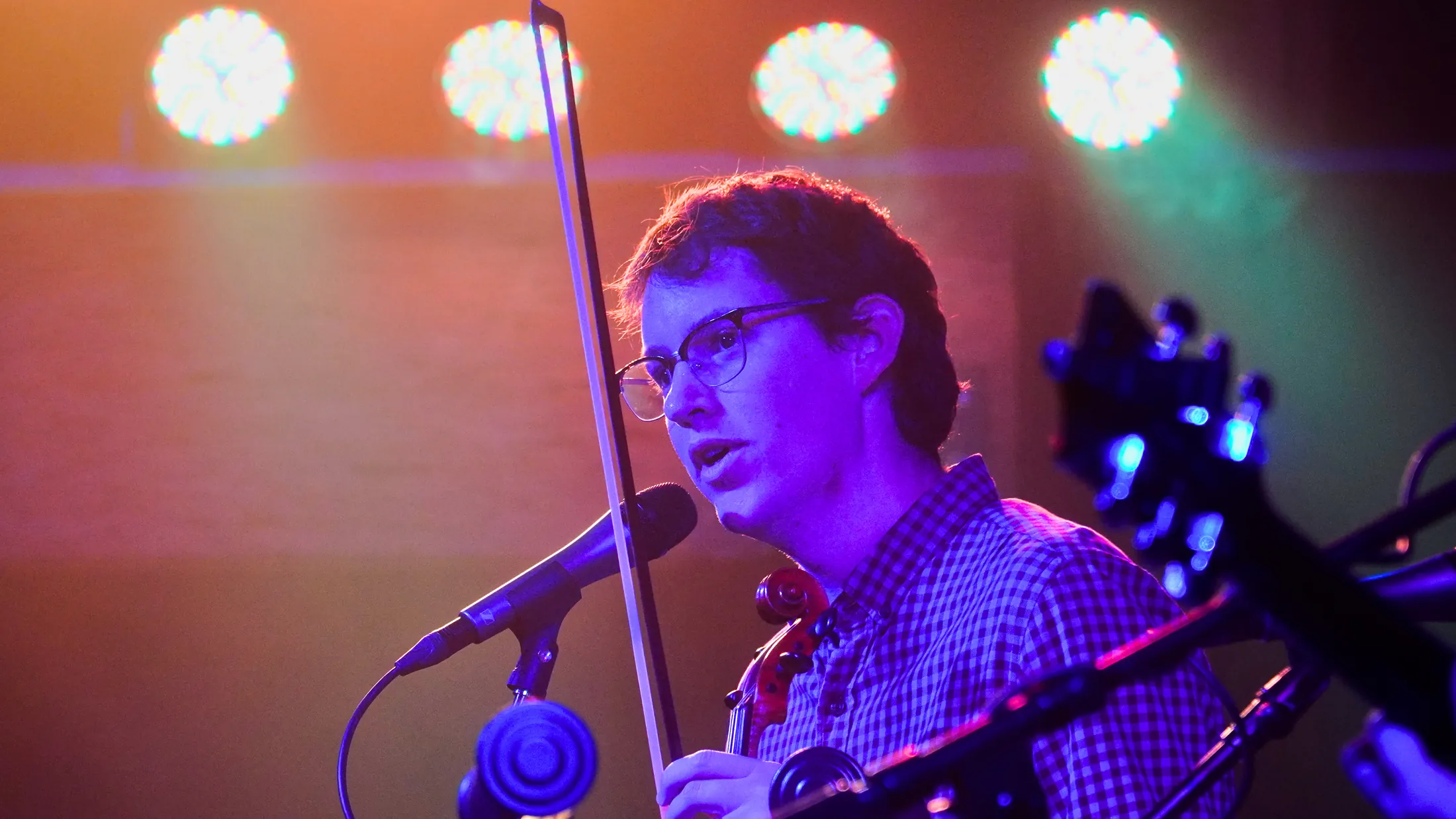 Violinist with bow raised under bright stage lights, Boise, Idaho concert photo by Rusty Rehl